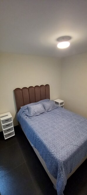 Une chambre à coucher comprenant un lit, une table de chevet et un meuble de rangement.
