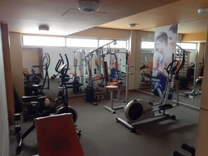 Une salle de sport équipée de divers appareils d’exercice, notamment des tapis de course, des appareils de musculation et des poids libres.