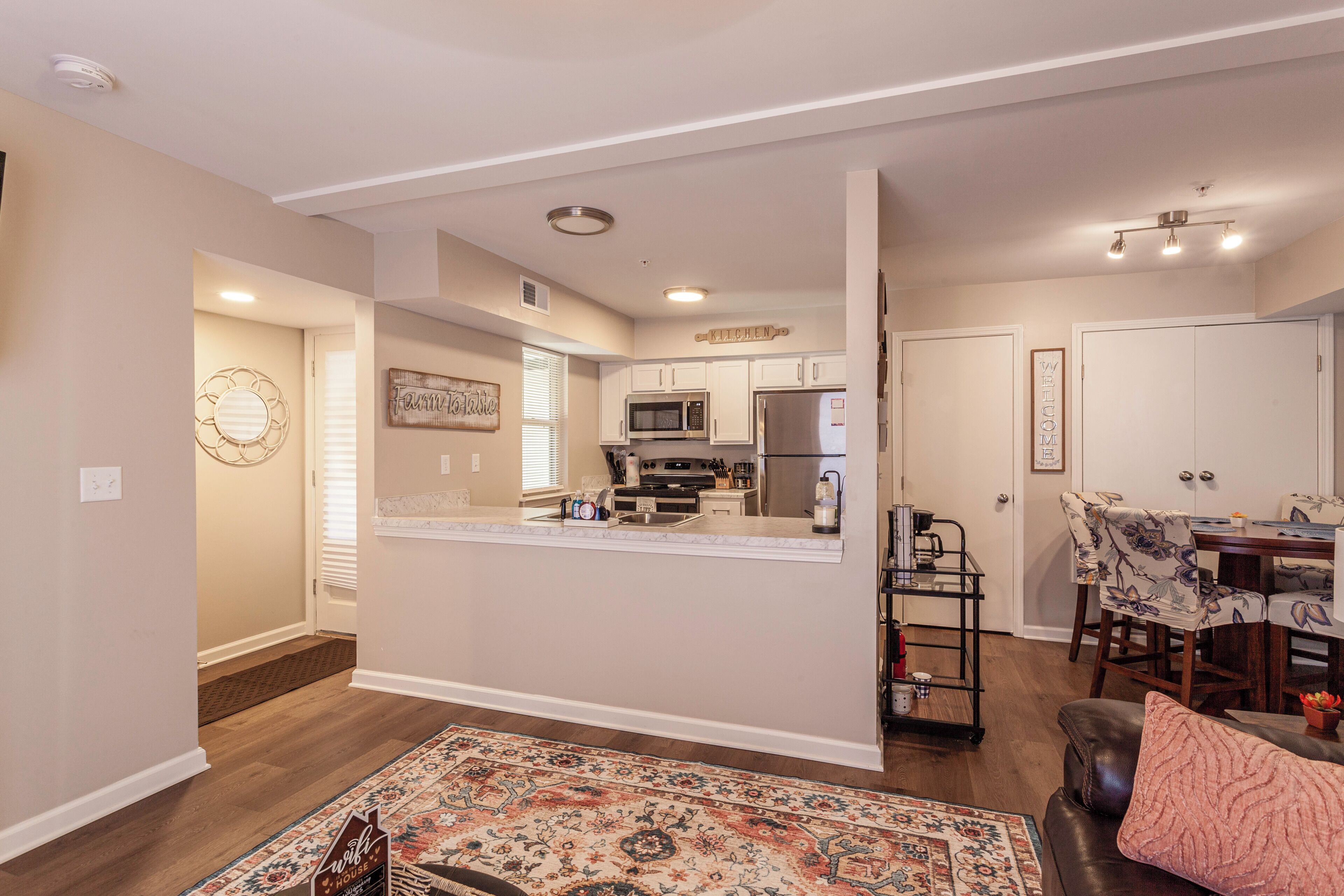 A modern kitchen with white cabinets, a stainless steel refrigerator, and a microwave.