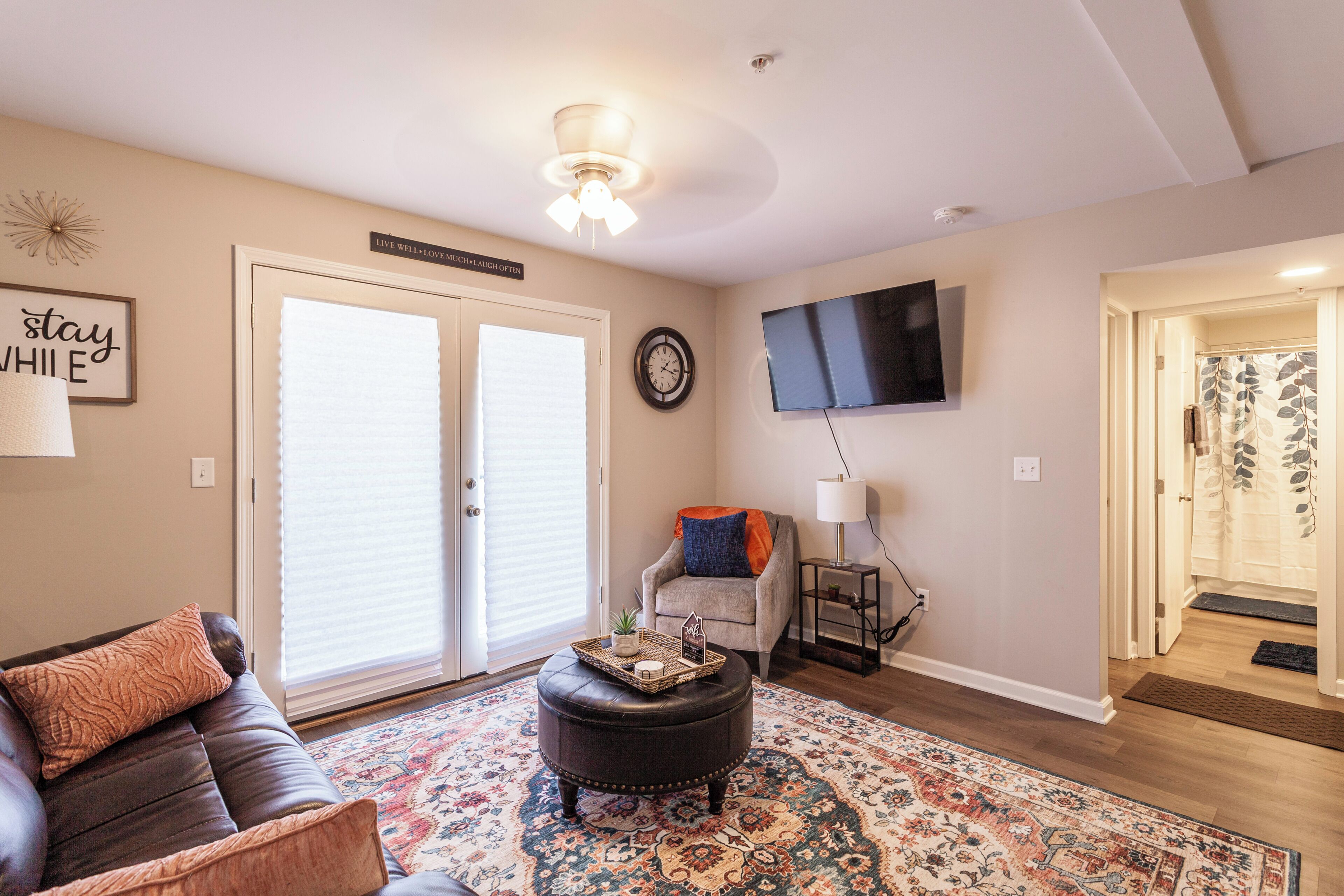 A living room with a leather sofa, ottoman, and a patterned rug.