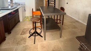 A kitchen with a dining table, stools, and a staircase leading to a loft.