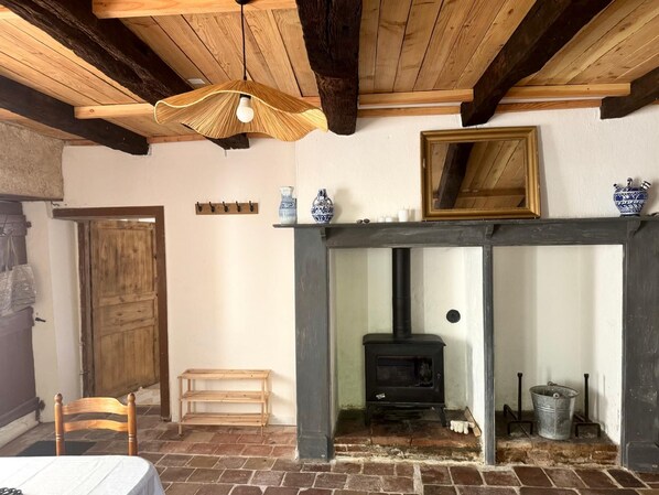 A rustic room with a fireplace, wooden beams, a bench, and a table.