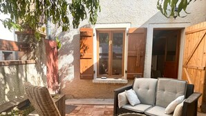 A patio with wicker furniture, a cushioned sofa, and a small table with candles.