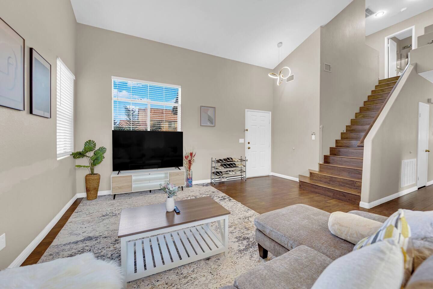 Un salon moderne doté d’un téléviseur à écran plat, d’un escalier et offrant une vue sur l’extérieur.