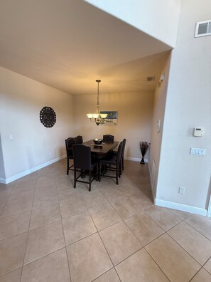A dining area with a table and chairs, a wall-mounted light fixture, and a decorative wall piece. - Spacious 4-bedroom house in peaceful Naples perfect for families (Naples)