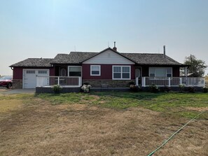 A two-story house with a front porch, a garage, and a small garden area.