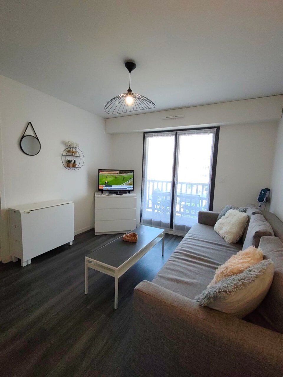 Un salon moderne doté d’un téléviseur à écran plat, d’un canapé, d’une table basse et d’un ventilateur de plafond.