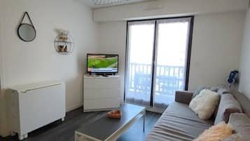 Un salon moderne doté d’un téléviseur à écran plat, d’un canapé, d’une table basse et d’un ventilateur de plafond.