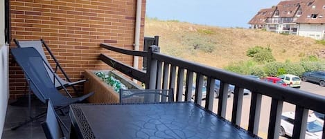 Un balcon avec une table et des chaises, un mur en briques et une vue sur un quartier résidentiel.
