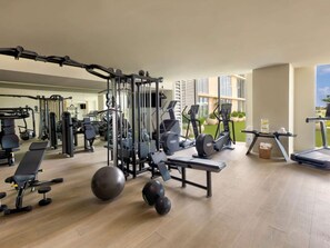 Ein modernes Fitnessstudio mit unterschiedlichen Trainingsgeräten, einem Spiegel und einem Laufband.