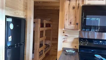 A compact kitchen with wooden cabinetry, a black refrigerator, and a stove.