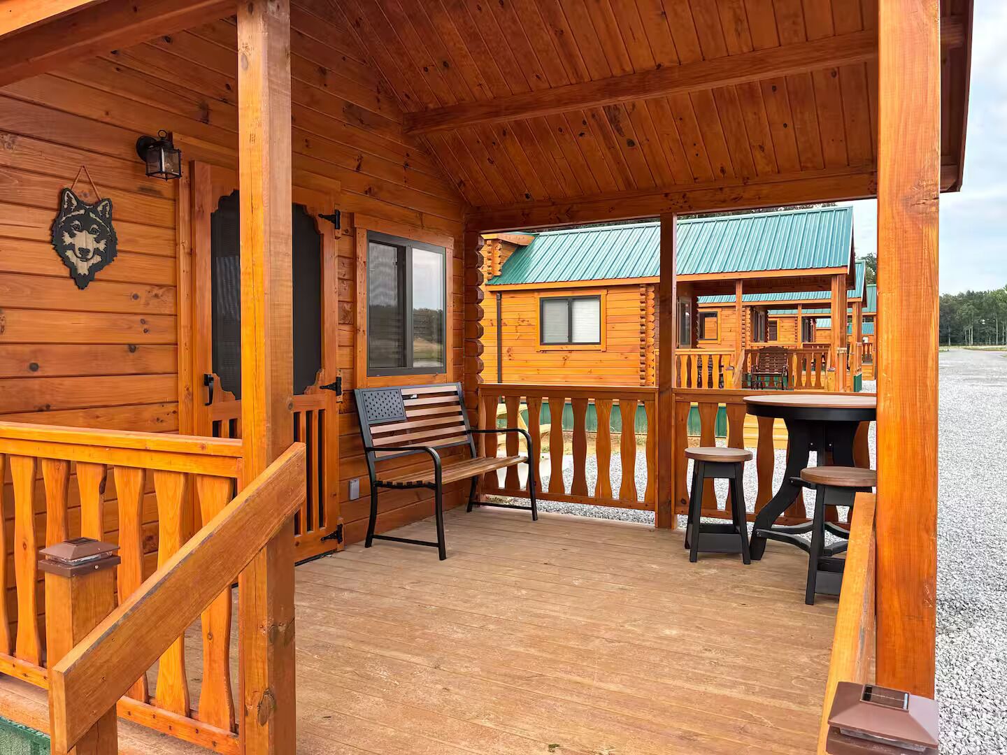 A wooden cabin with a porch, a bench, and a table.