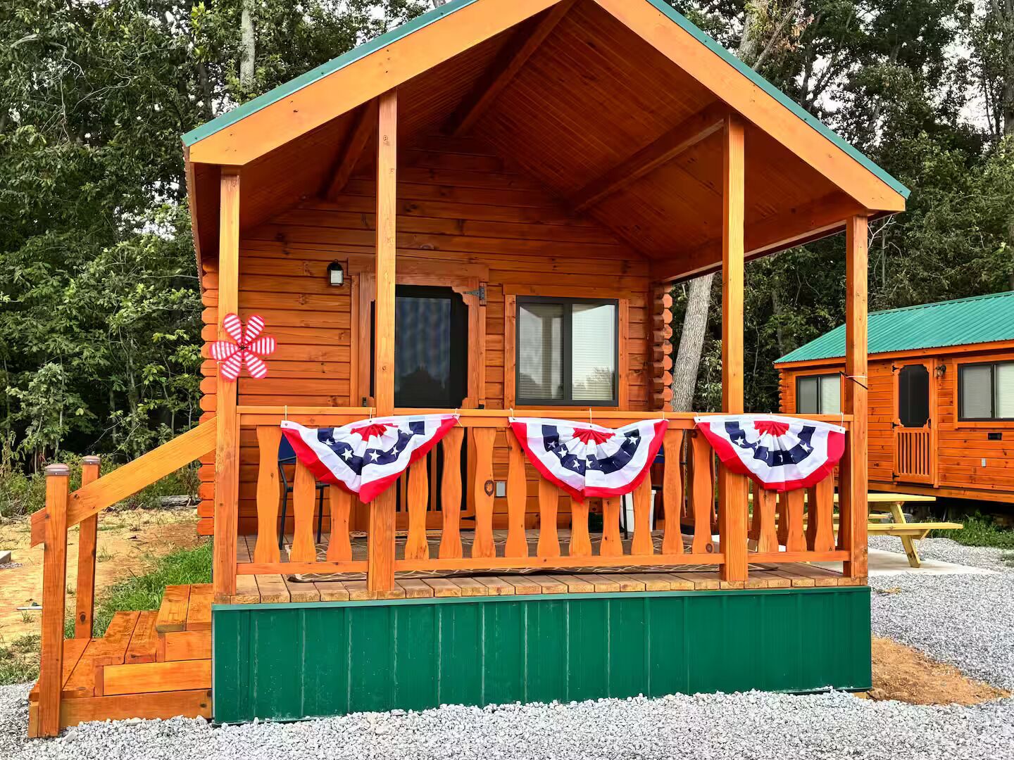 A wooden cabin with a porch, a green awning, and a flag decoration.