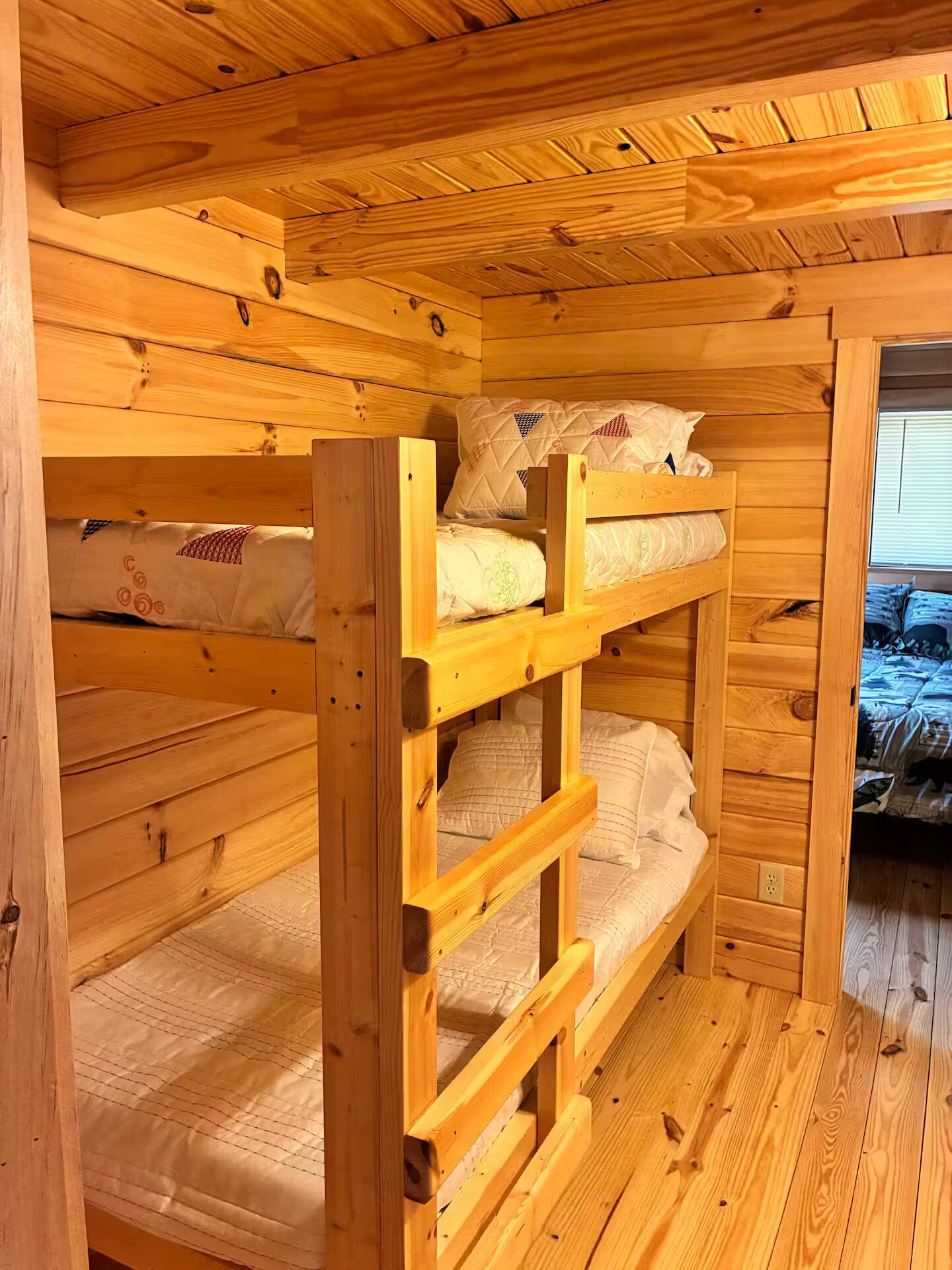 A wooden bunk bed room with a window and a door.