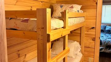 A wooden bunk bed room with a window and a door.