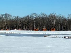 A row of wooden cabins in a snowy landscape with a clear sky.