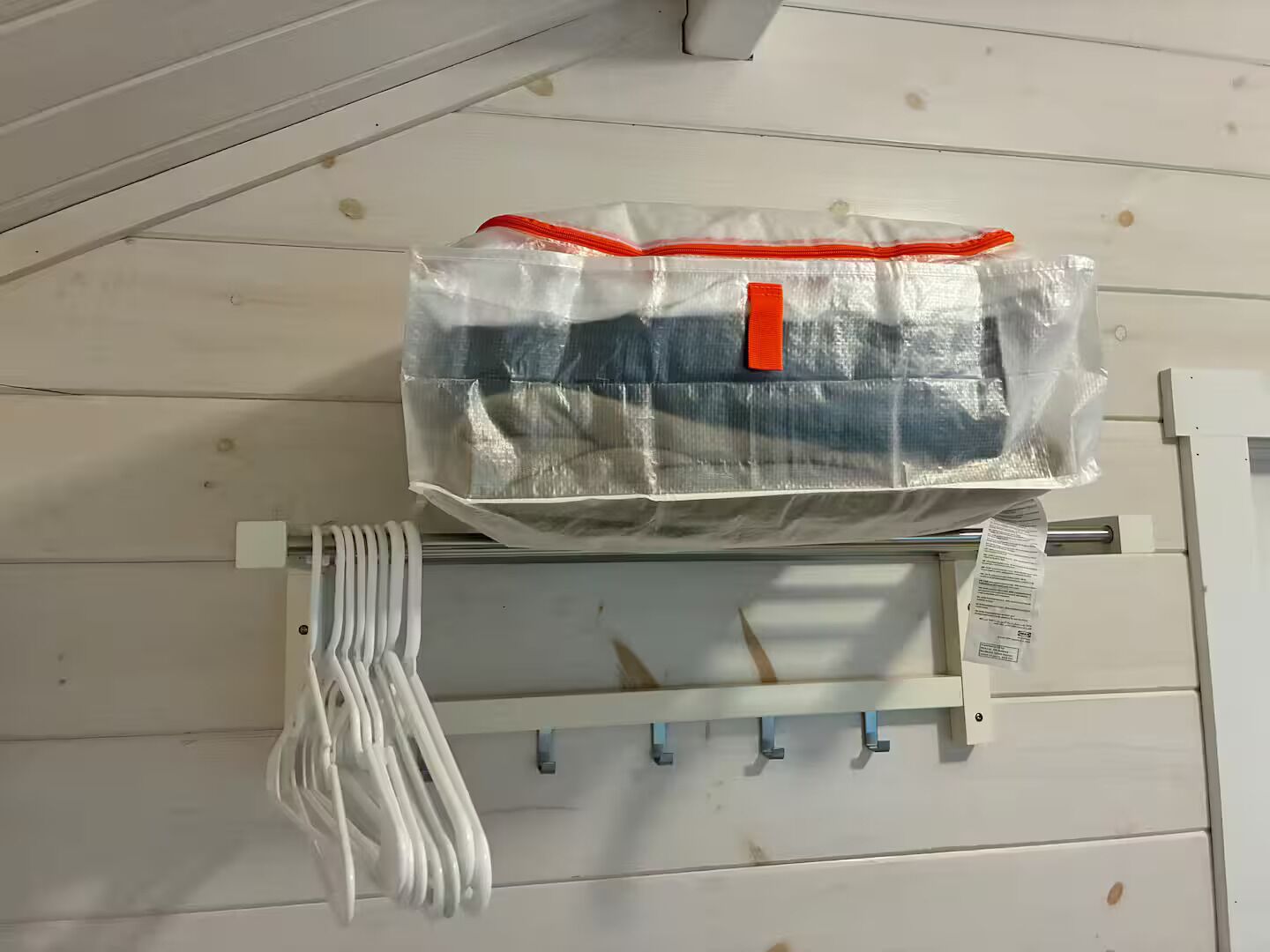 A plastic bag with a red strap hanging on a metal rack.
