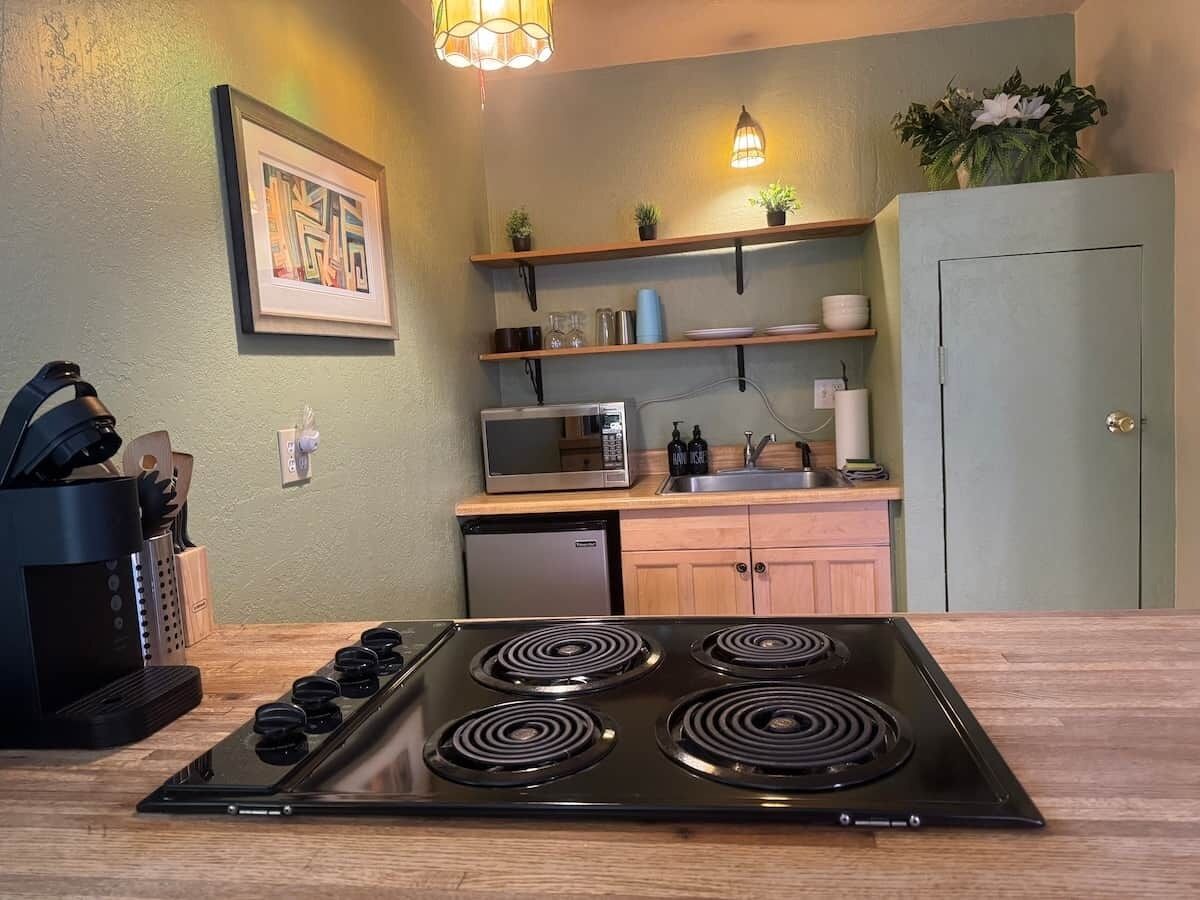 A kitchen with a black stove, wooden countertop, and a microwave above a sink.
