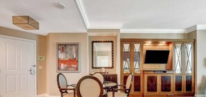 Ein Hotelzimmer mit Essbereich, einem Flachbildfernseher und einem großen Spiegel.