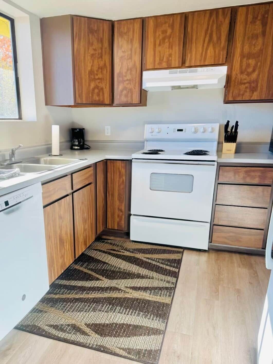 A compact kitchen with wooden cabinets, a white stove, and a coffee maker.
