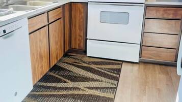 A compact kitchen with wooden cabinets, a white stove, and a coffee maker.