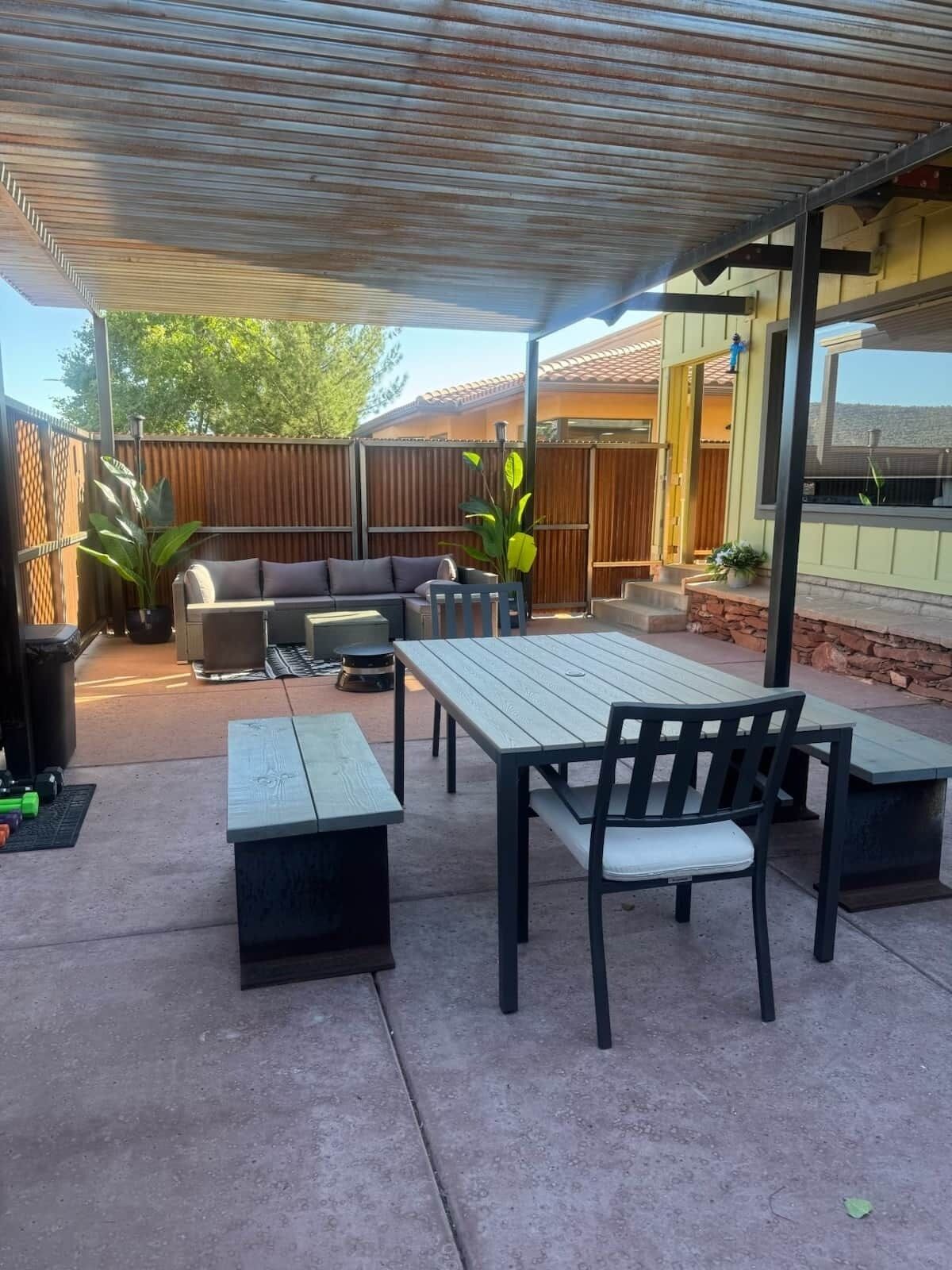 Un espace extérieur aménagé en terrasse, avec un coin salon couvert, une table à manger et un barbecue.