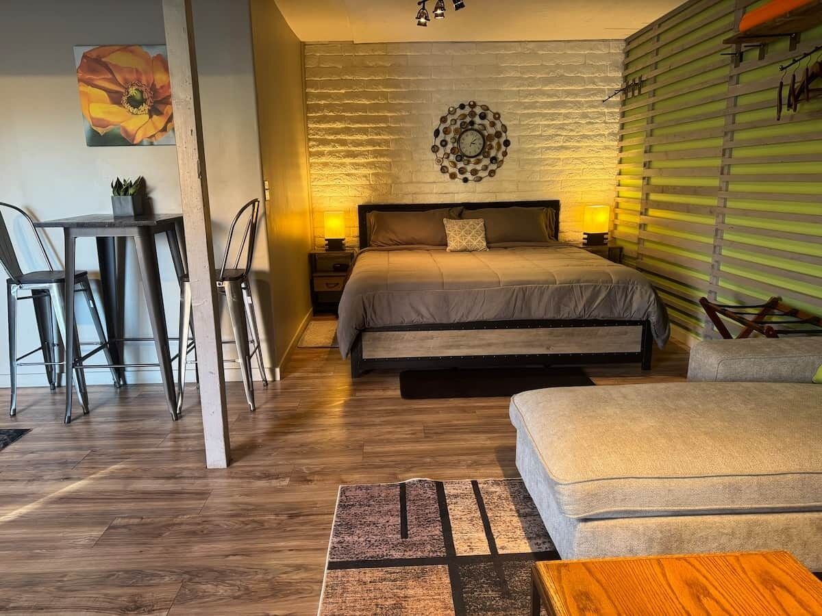 A bedroom with a bed, bedside tables, a chair, a small table, and a wall clock.