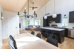 A modern kitchen with a central island, black cabinets, and stainless steel appliances. - Nature Getaway & Spa | Conifer (Notre-Dame-de-la-Merci)