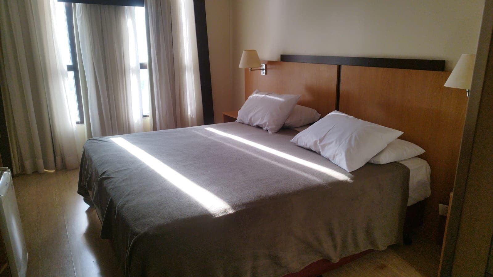 Una habitación de hotel con cama, cortinas y mesita de noche.