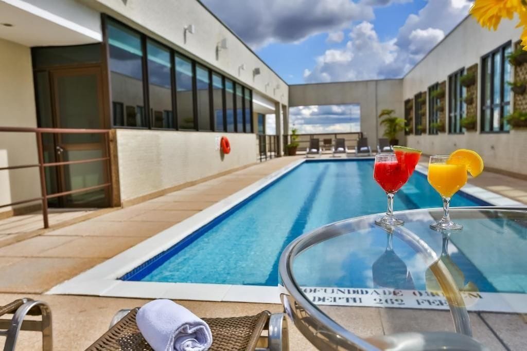 A swimming pool with lounge chairs and a glass table with drinks.