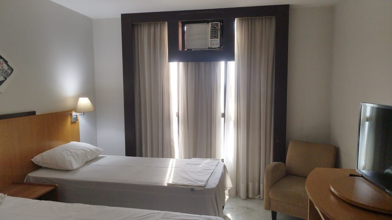 Habitación de hotel con dos camas, un televisor, una silla y un equipo de aire acondicionado.