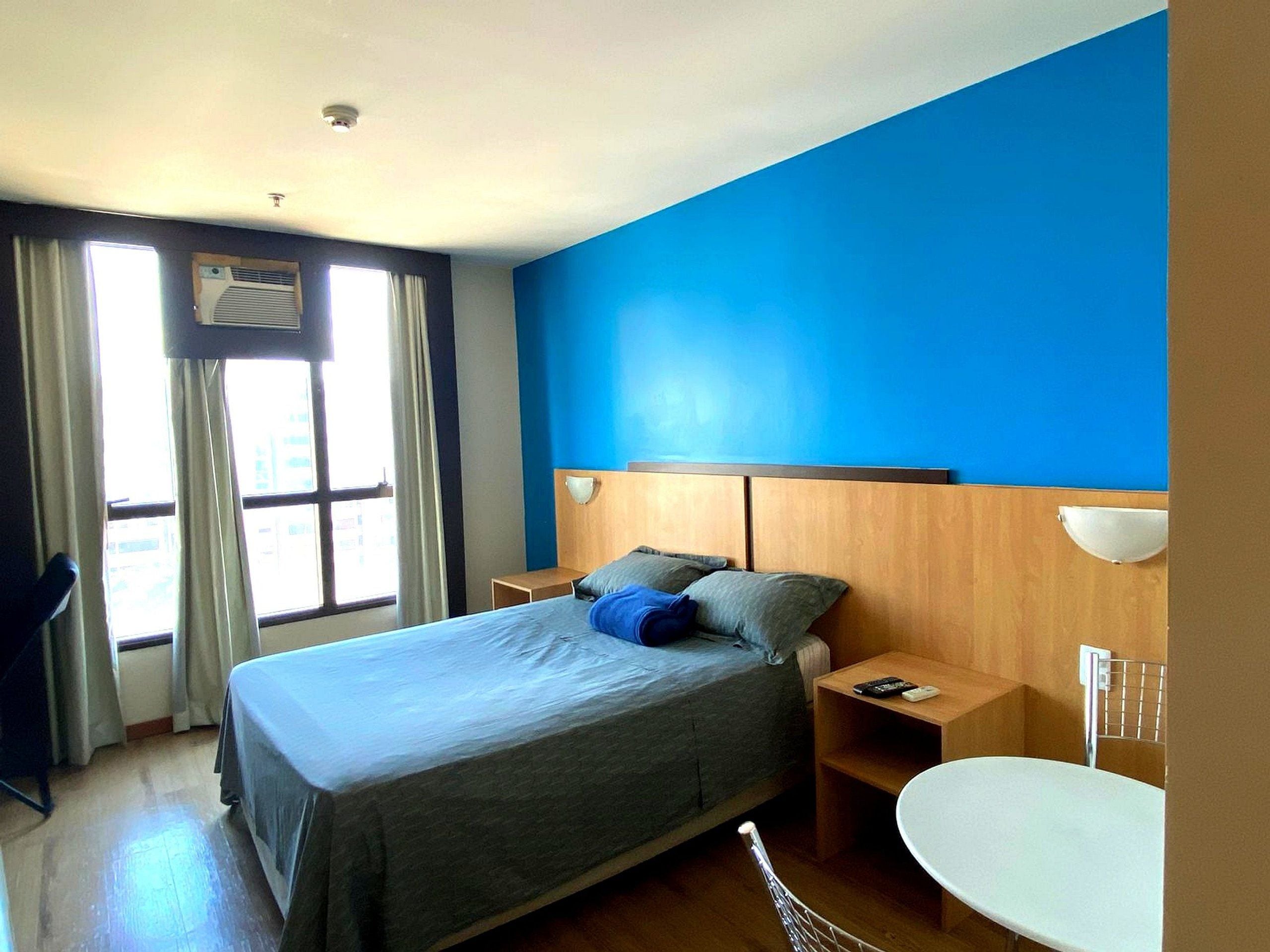 Habitación de hotel con cama, mesitas de noche, cortinas y baño con bañera.