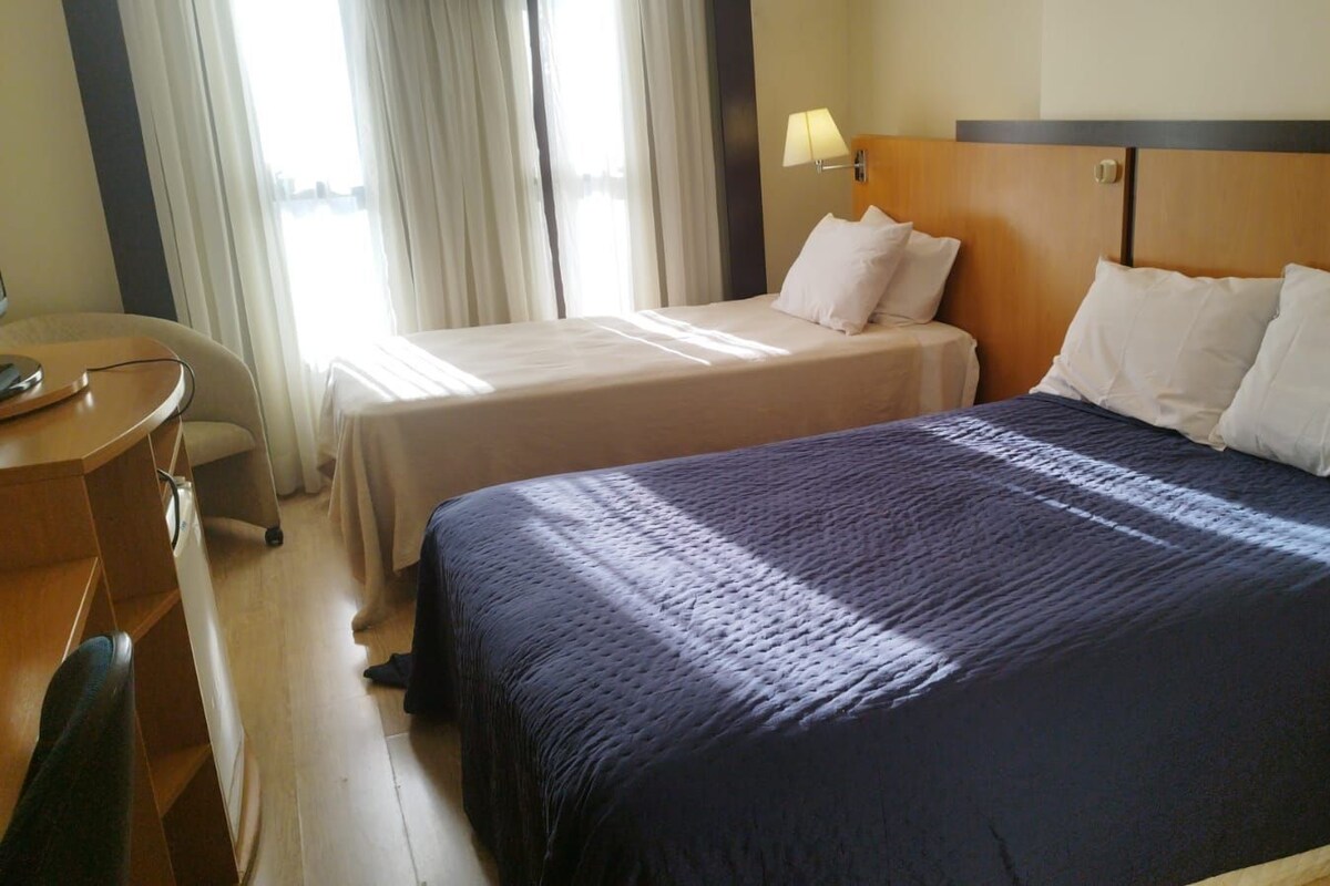Une chambre d’hôtel avec deux lits, un bureau et une chaise.