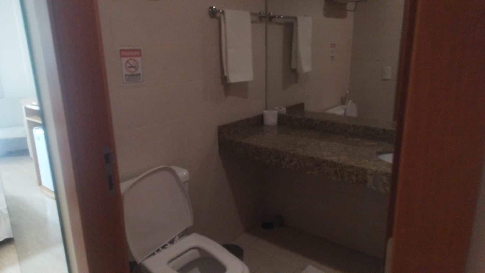 A small bathroom with a toilet, a sink, and a mirror.