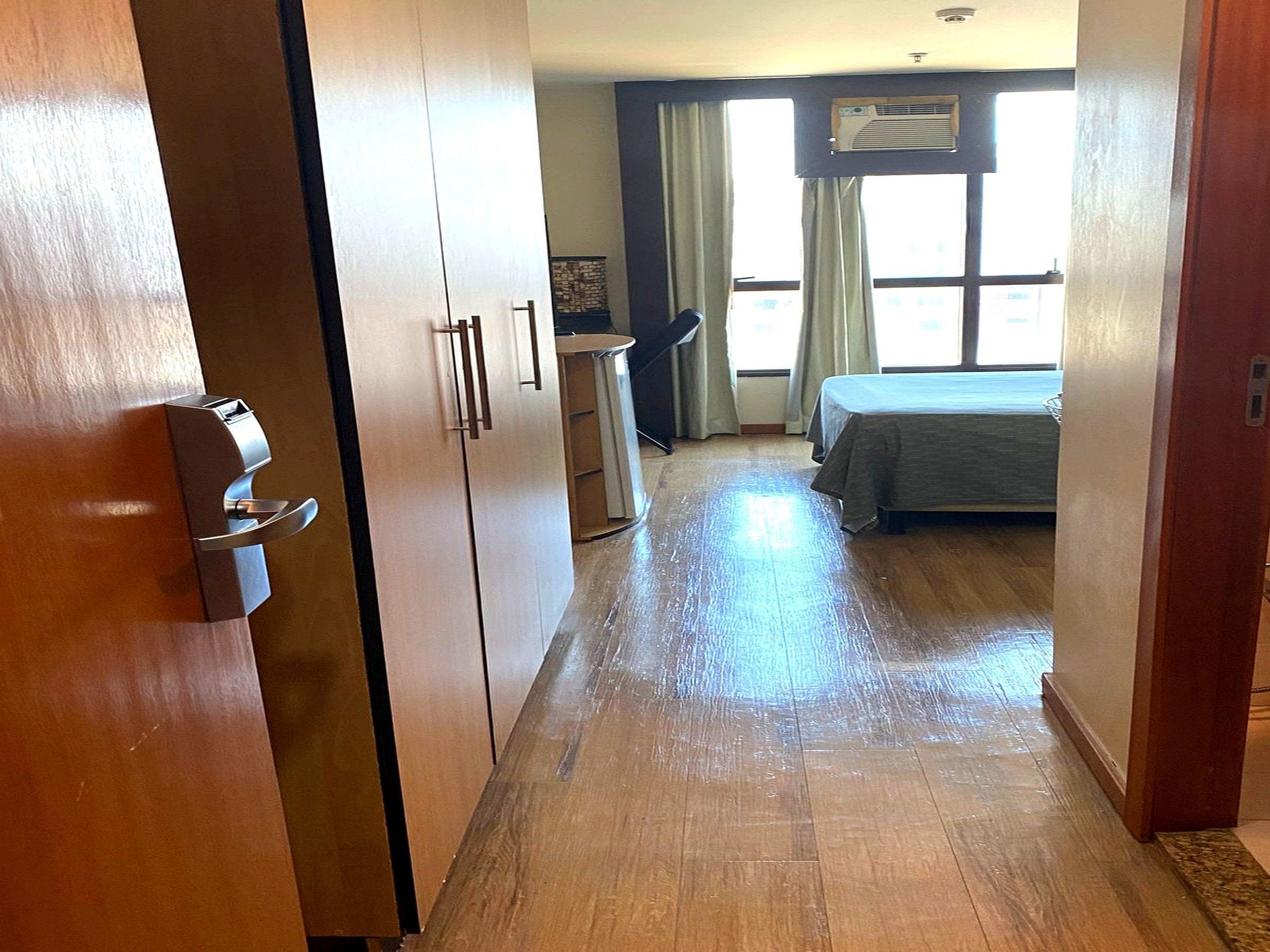 A hotel room with a bed, a desk, and a window with curtains.
