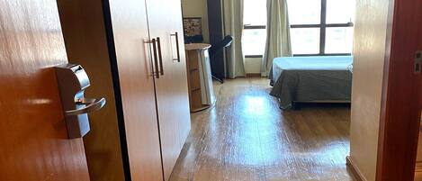 A hotel room with a bed, a desk, and a window with curtains.
