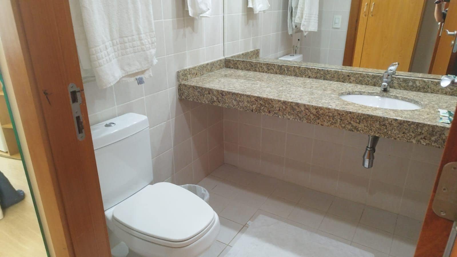 Een badkamer met toilet, wastafel en spiegel.