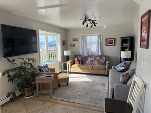 A living room with a sofa, armchairs, a coffee table, a TV, and a potted plant.