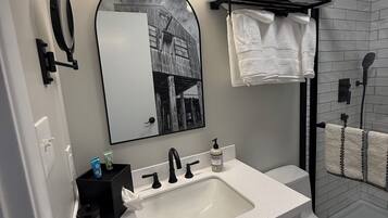 A modern bathroom with a white sink, black faucets, a mirror, and a towel rack.