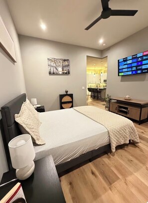 A modern bedroom with a bed, bedside table, lamp, and a TV mounted on the wall. - Modern Peaceful Apartment in Downton Dallas - City Views - Parking - Balcony (Dallas)