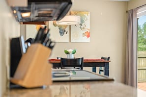 Un coin repas comprenant une table, des chaises, un vase avec une fleur et un mur décoré d’œuvres d’art.