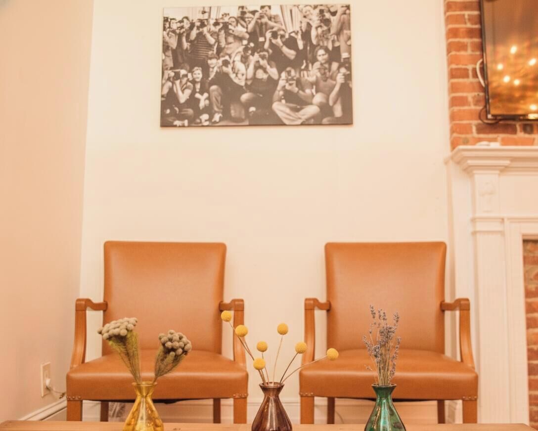 Una habitación con dos sillones de cuero marrón, una mesa con jarrones y una fotografía blanco y negro en la pared.