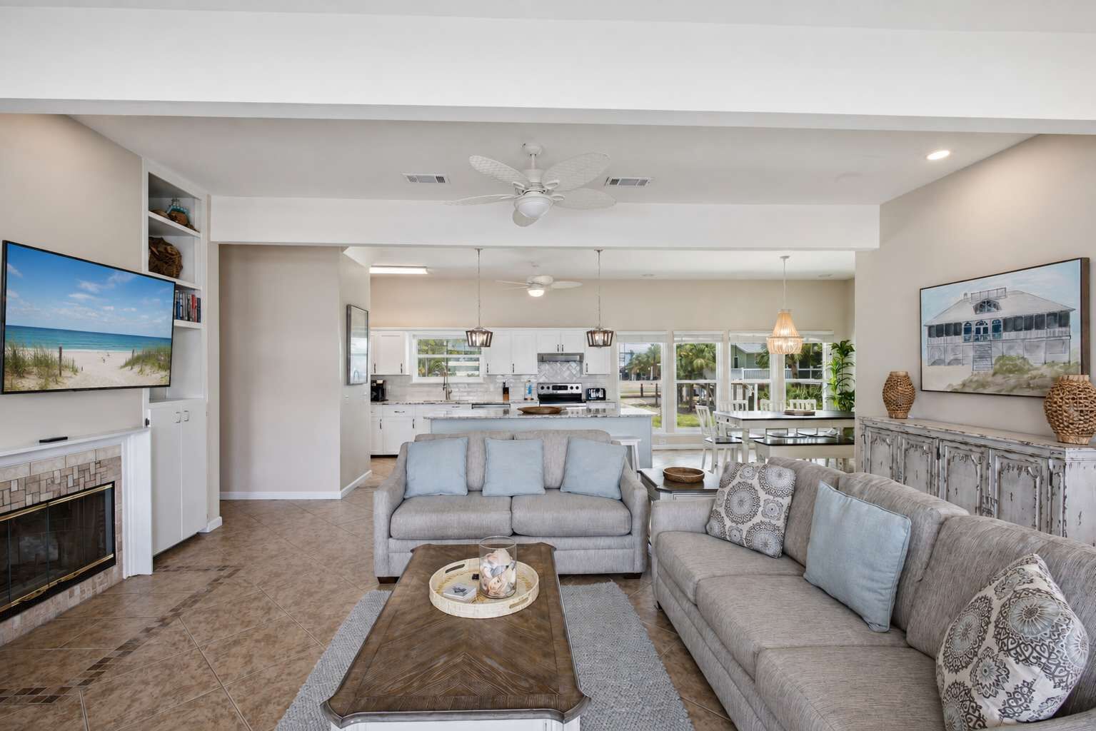 A spacious living room with a fireplace, a sofa set, a coffee table, and a television mounted on the wall.