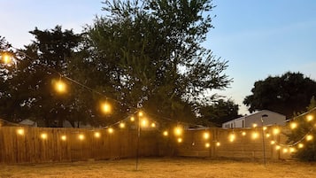 Ein grünes Freigelände mit Lichterketten und einem Holzzaun.