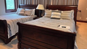 Quarto com duas camas de madeira, roupa de cama listrada e uma janela com cortinas.