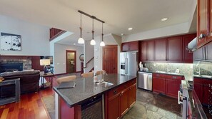 A modern kitchen with a central island, built-in appliances, and a stone backsplash. - Timbers! Luxury 4+ Bdrm condo in this fantastic community on the golf course (Mammoth Lakes)