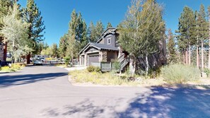 A two-story house with a stone facade, a front porch, and a driveway leading to a parking area. - Timbers! Luxury 4+ Bdrm condo in this fantastic community on the golf course (Mammoth Lakes)