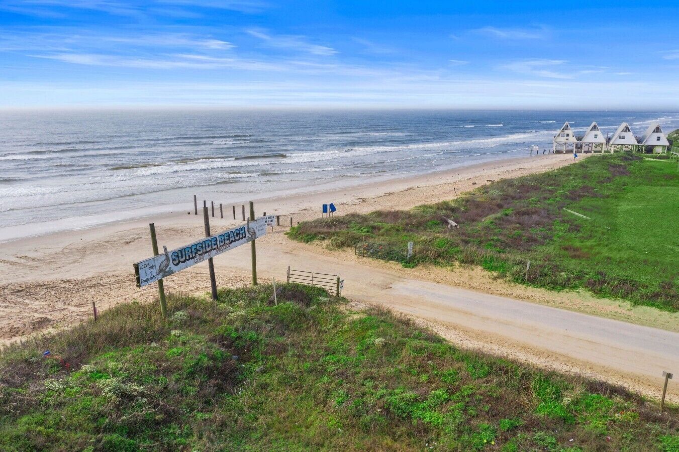A beach with a sign indicating 'Surfside Beach' and a path leading to beach huts.