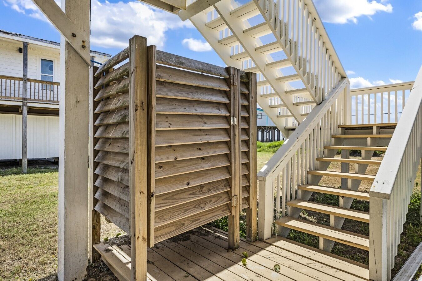 A wooden staircase leading to a deck area with a railing.