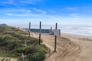 A beach sign with 'SURFSIDE BEACH' and 'Gulf of Mexico' text, a sandy beach, and the ocean.